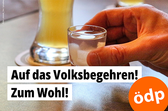 Eine Hand hält ein volles Schnapsglas und lädt zum Anstoßen ein