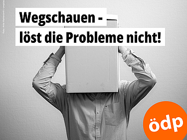 Das schwarz-weiß-Foto zeigt einen Mann, der sich einen großen Karton über den Kopf gezogen hat und ihn mit beiden Händen festhält